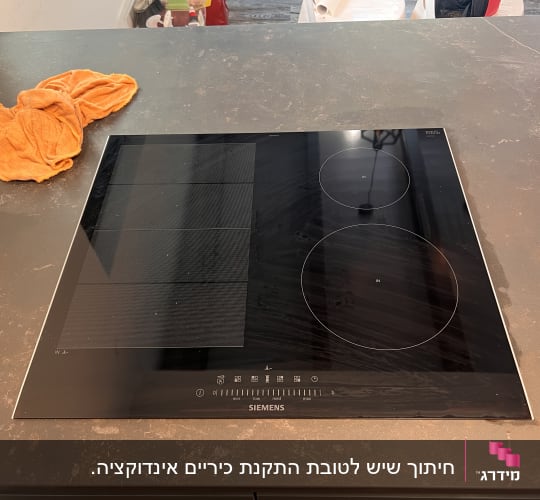 כיריים על משטח שיש כהה עם מטלית כתומה